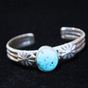 Sterling silver turquoise cuff bracelet with stamped silver flower designs on black background. Vintage Sterling Silver Turquoise Cuff Bracelet